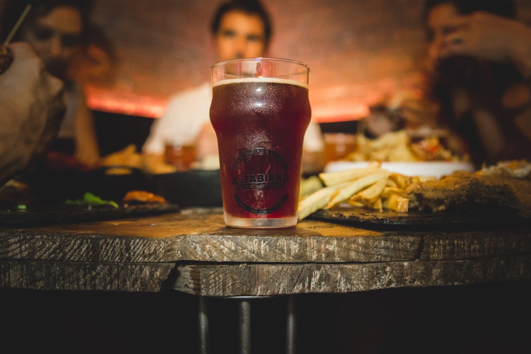 Pinta de cerveza tostada sobre mesa de madera